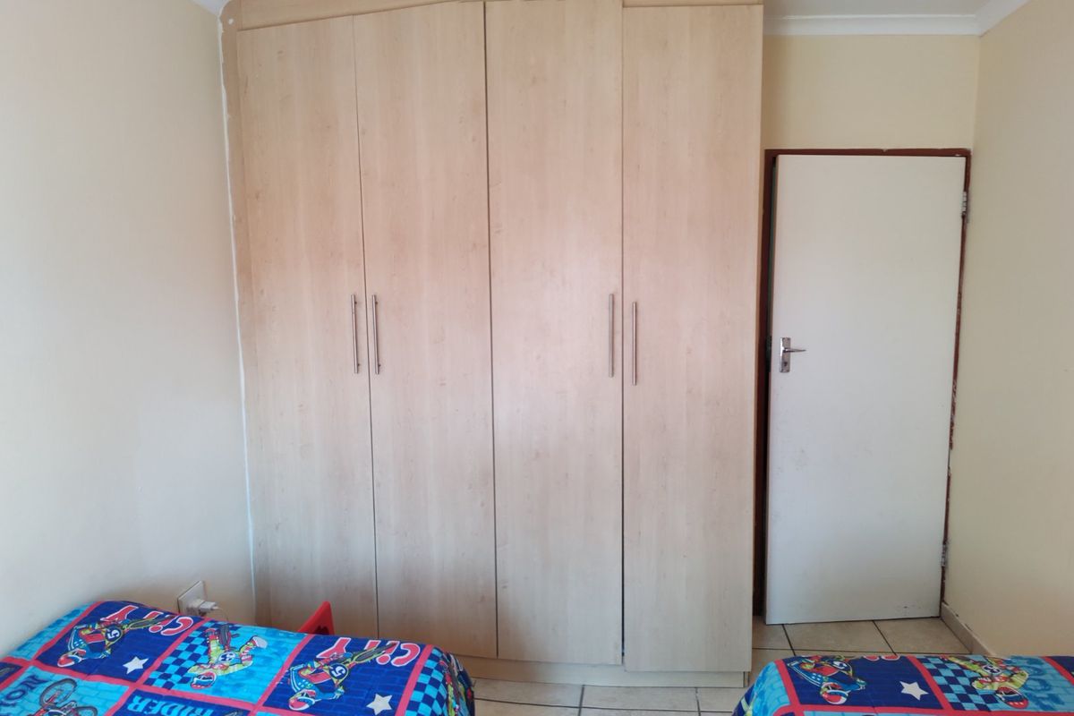 A bedroom featuring light wood-finish built-in wardrobes and tiled flooring, providing functional storage space.