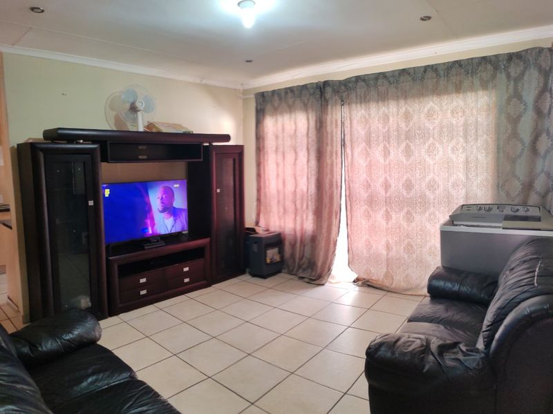 A living room featuring ceramic tiled flooring and coved ceilings, providing a functional space with potential for cosmetic updates to enhance the interior aesthetic.
