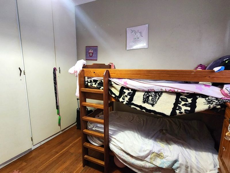 A bedroom featuring hardwood flooring and built-in cupboards, providing functional storage space.