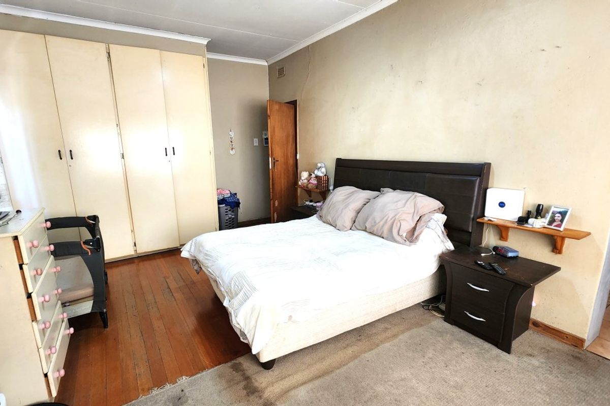 A bedroom featuring wooden flooring, built-in cupboards, and coving. The room requires cosmetic updates to the walls and finishes to improve its overall condition.