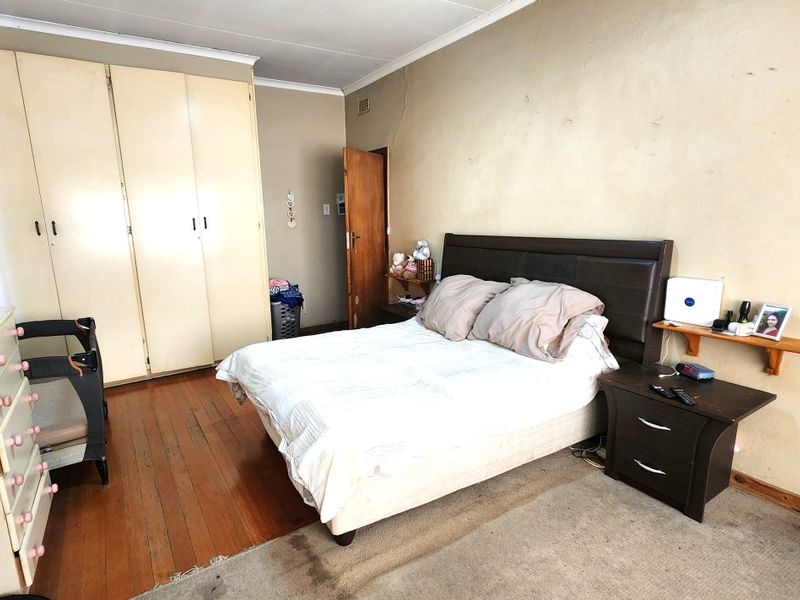 A bedroom featuring wooden flooring, built-in cupboards, and coving. The room requires cosmetic updates to the walls and finishes to improve its overall condition.