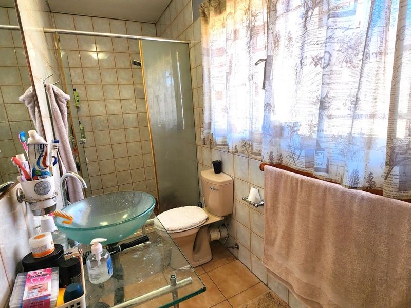 A functional bathroom featuring a glass vessel sink, vanity, and a shower enclosure with tiled walls and flooring.