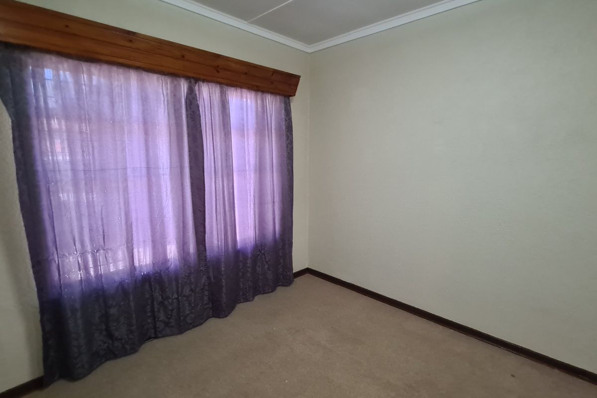 An empty bedroom featuring carpet flooring and a timber curtain pelmet, offering a blank canvas for personalization.