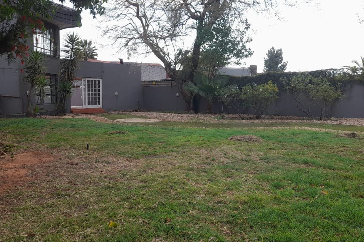 A spacious rear garden featuring a lawn area, perimeter wall, and access to the main dwelling via french doors.