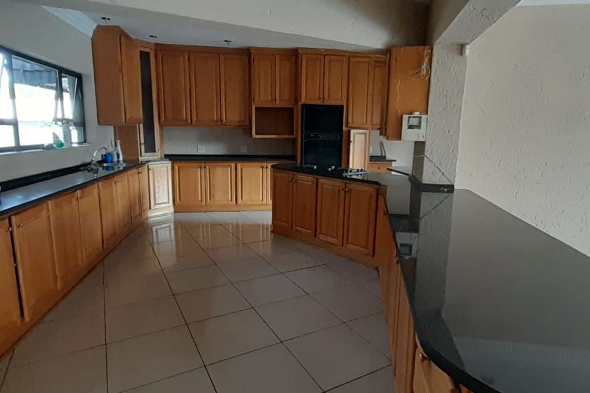 Spacious kitchen featuring wooden cabinetry, granite countertops, a breakfast bar, and tiled flooring, offering a functional layout ready for modern updates.