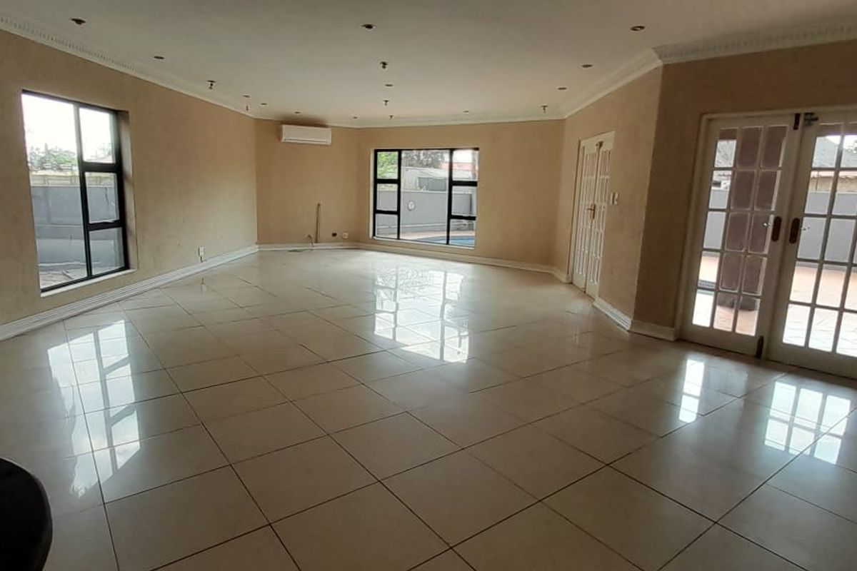 Spacious, empty living area featuring polished tiled floors, recessed lighting, air conditioning, and direct access to the patio through double french doors.