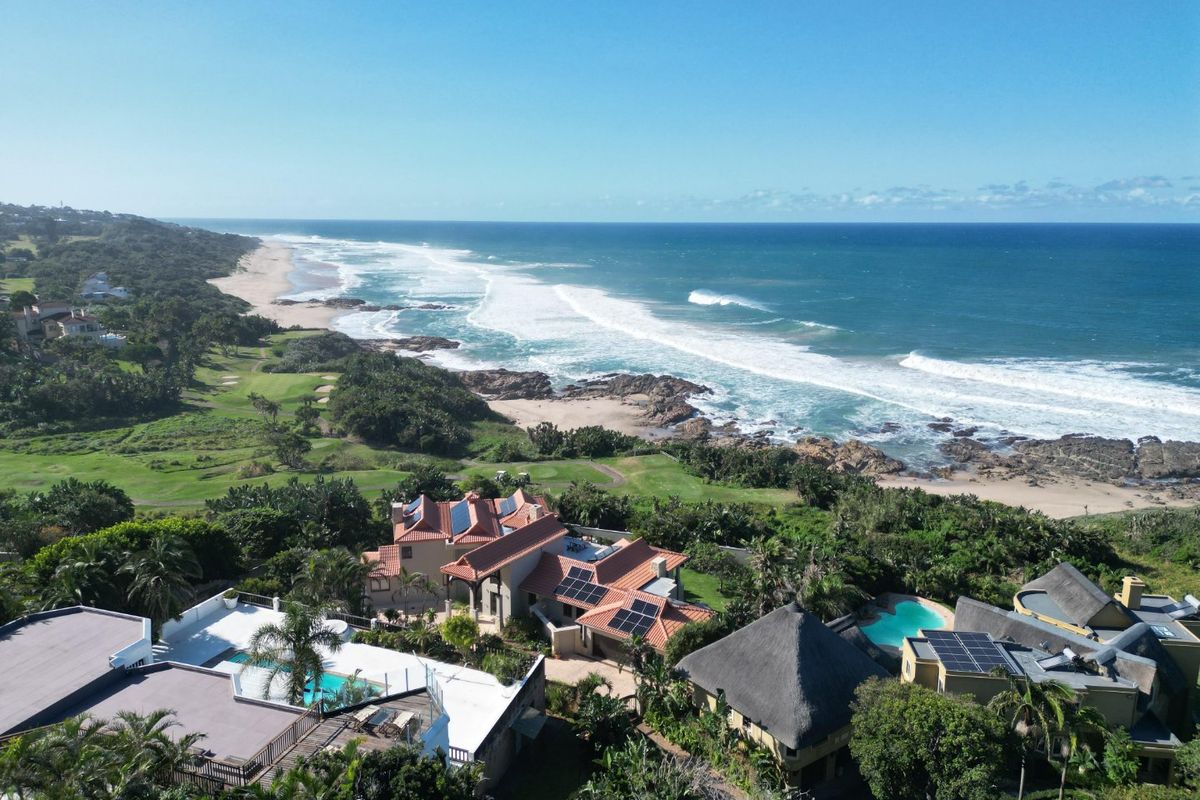 Aerial view of a coastal residential property featuring multiple dwellings, swimming pools, solar installations, and direct proximity to the ocean and golf course.