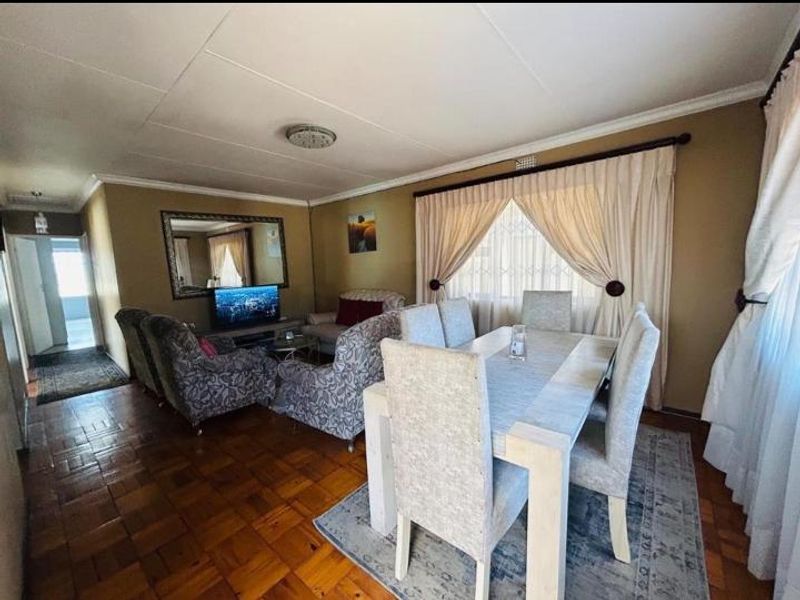 Open plan living and dining area featuring classic parquet flooring and neutral wall tones, providing a functional and connected space for daily living.