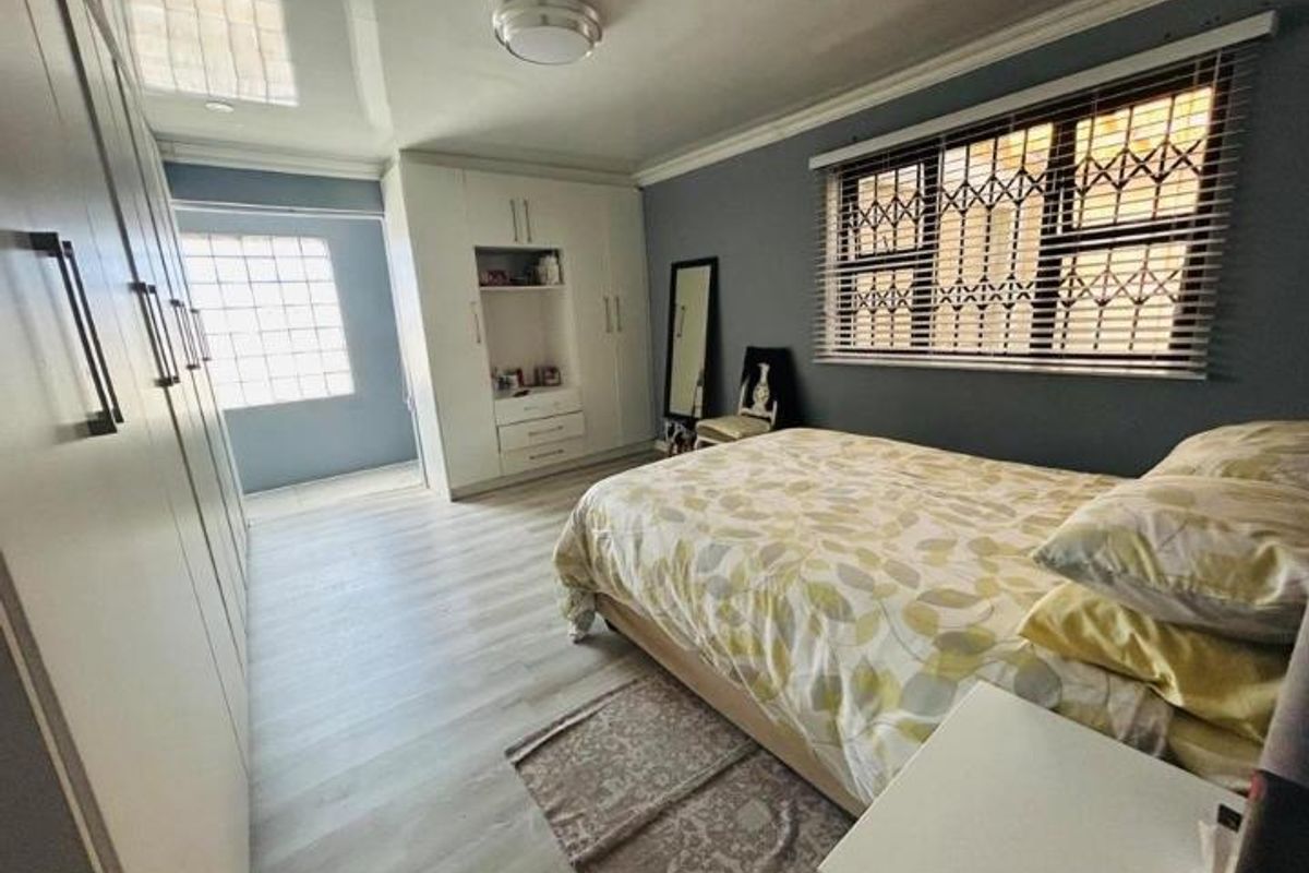 A well-maintained bedroom featuring extensive built-in cabinetry, laminate flooring, and a glass block window providing natural light.