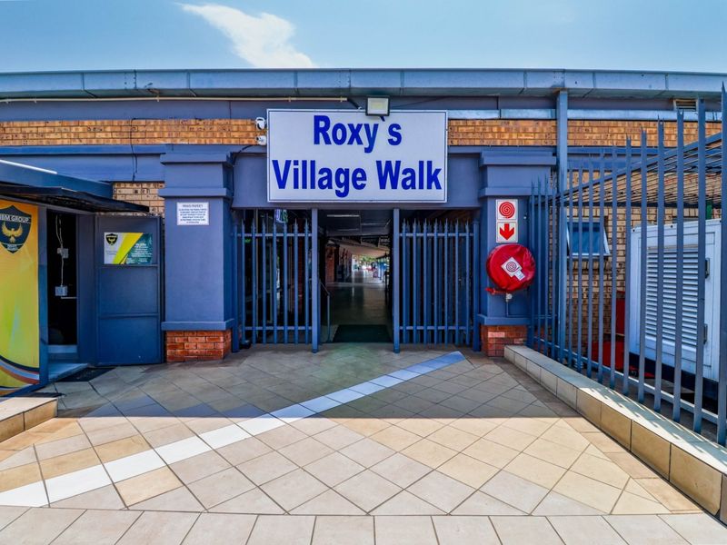 Front entrance to Roxy's Village Walk commercial property, featuring a secure gated access point, paved walkway, and prominent building signage.