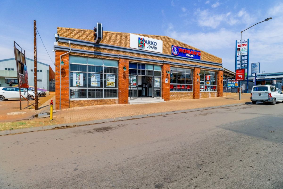 Front exterior view of a commercial building featuring brick construction, large display windows, and prominent signage for retail tenants.