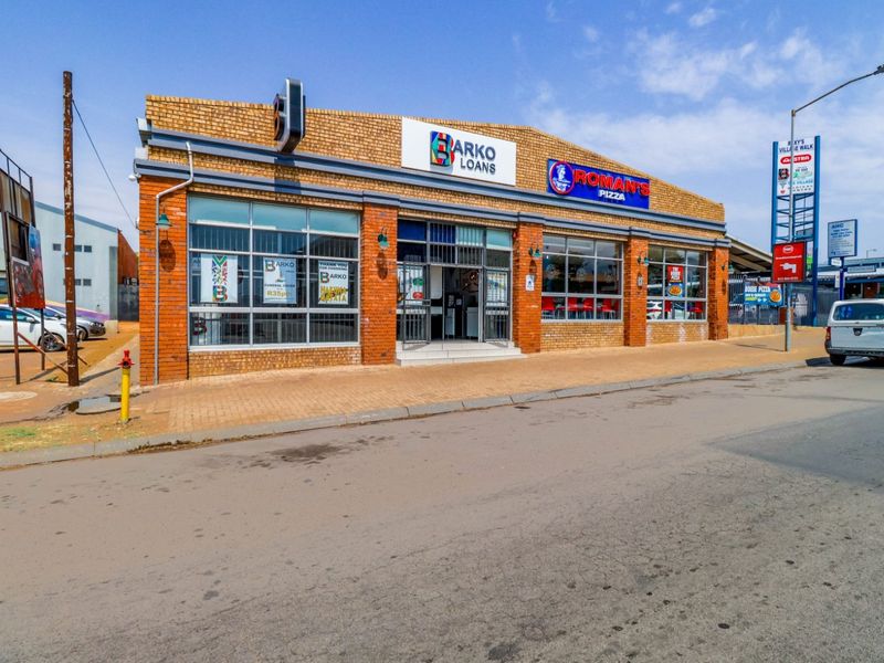 Front exterior view of a commercial building featuring brick construction, large display windows, and prominent signage for retail tenants.