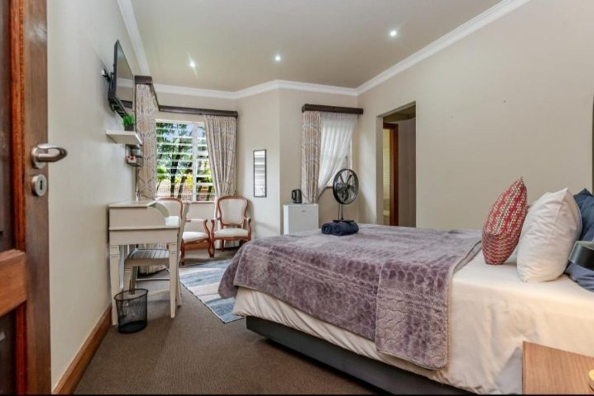 A well-lit bedroom featuring recessed downlighting, coved ceilings, and louvered windows, providing a comfortable and functional sleeping space.