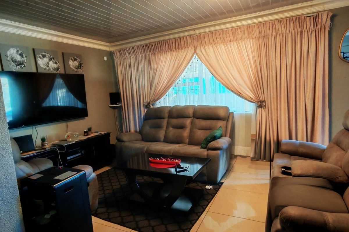 A living room featuring tiled flooring, a tongue and groove ceiling, and a decorative crystal chandelier.