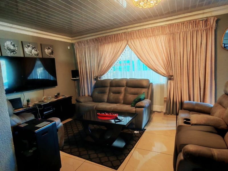 A living room featuring tiled flooring, a tongue and groove ceiling, and a decorative crystal chandelier.