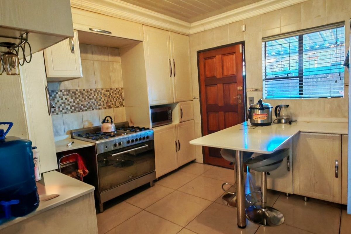Functional kitchen featuring built-in cabinetry, a gas stove with oven, tiled backsplash, and a breakfast bar area with tiled flooring.