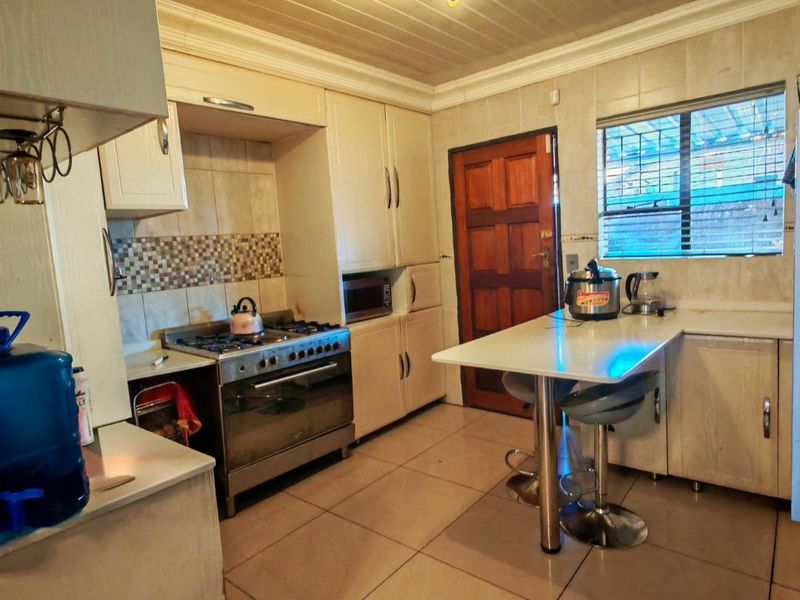 Functional kitchen featuring built-in cabinetry, a gas stove with oven, tiled backsplash, and a breakfast bar area with tiled flooring.