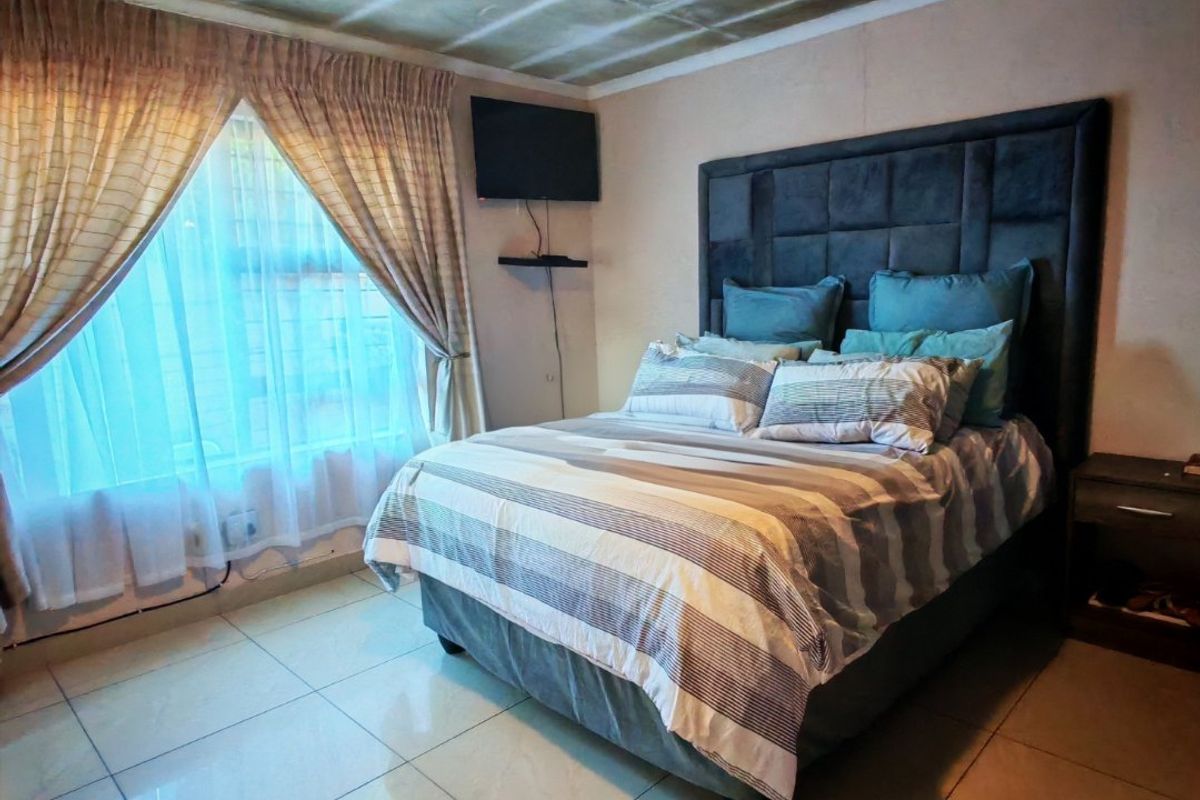 A bedroom featuring tiled flooring and a wall-mounted television bracket, requiring ceiling repairs and cosmetic updates to improve the overall finish.