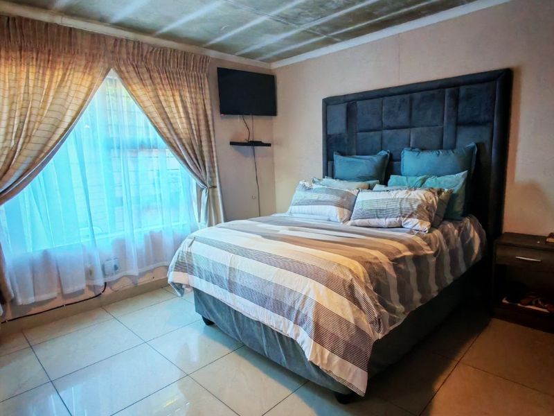 A bedroom featuring tiled flooring and a wall-mounted television bracket, requiring ceiling repairs and cosmetic updates to improve the overall finish.