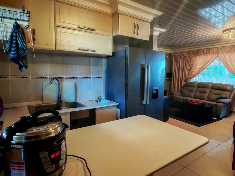 Open plan kitchen and living area featuring built-in cabinetry, tiled backsplash, and tiled flooring with a coved ceiling design.