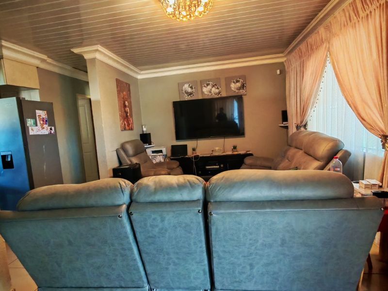 A living room featuring a tongue and groove ceiling, crown molding, and tiled flooring, providing a functional and lived-in space.