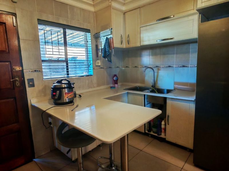 Compact kitchen featuring built-in cabinetry, tiled backsplash, and a breakfast bar counter. Requires minor repairs to the under-sink cabinetry.
