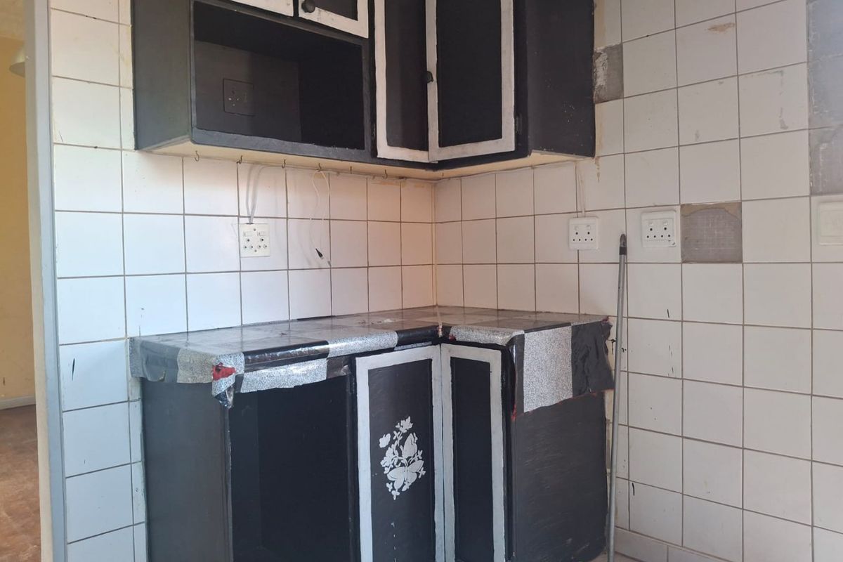 A dated kitchen area featuring built-in cabinetry and tiled splashbacks, currently in need of significant renovation and cosmetic updates to improve functionality and aesthetic appeal.
