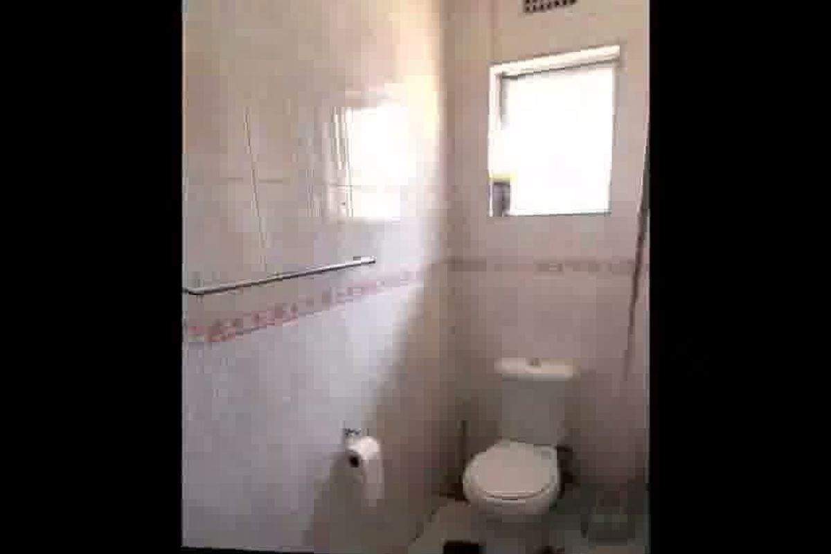A compact bathroom featuring tiled walls, a standard toilet, and a wall-mounted towel rail.