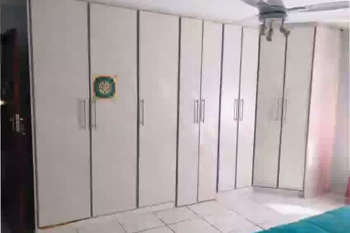 Bedroom featuring extensive built-in cupboard storage, tiled flooring, and a ceiling fan.
