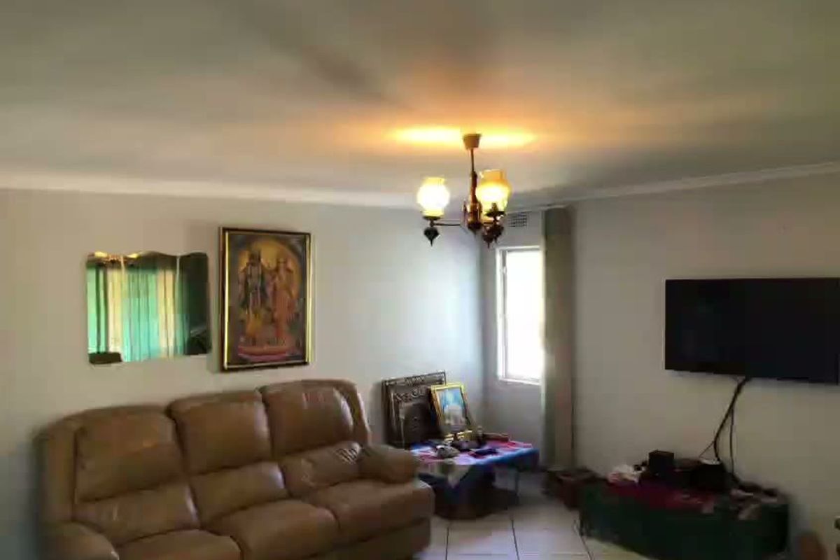 A living room featuring tiled flooring, ceiling cornice, and a central light fixture, providing a functional space for relaxation.