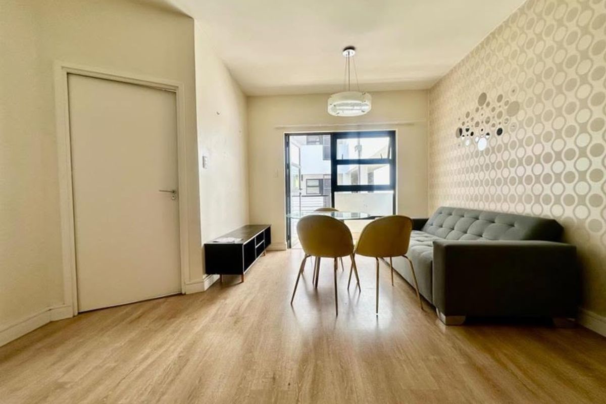 A living room featuring laminate flooring, a pendant light fixture, and a sliding glass door providing access to an outdoor area.