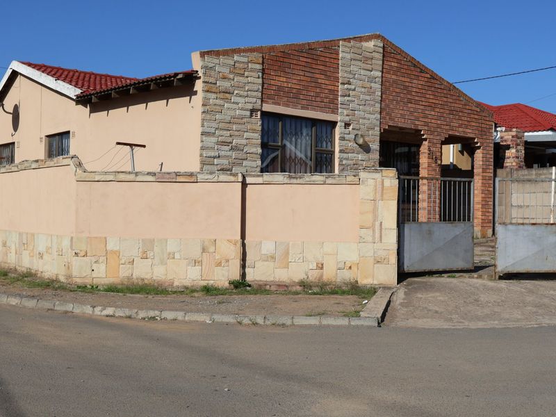 Front exterior view of a house featuring a combination of face brick and stone cladding, with a perimeter wall and metal driveway gate.