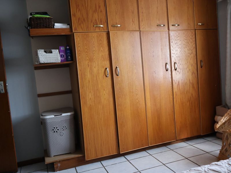 Bedroom featuring extensive built-in wooden cabinetry and tiled flooring, offering ample storage space.
