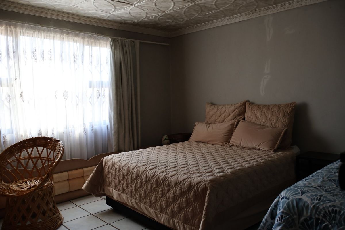 A bedroom featuring tiled flooring and decorative ceiling tiles, requiring cosmetic updates to the wall finishes.