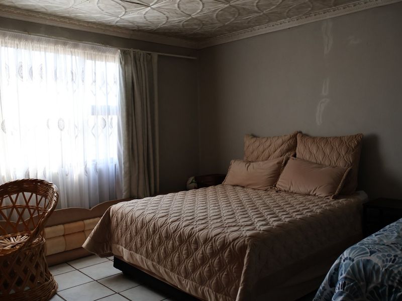 A bedroom featuring tiled flooring and decorative ceiling tiles, requiring cosmetic updates to the wall finishes.