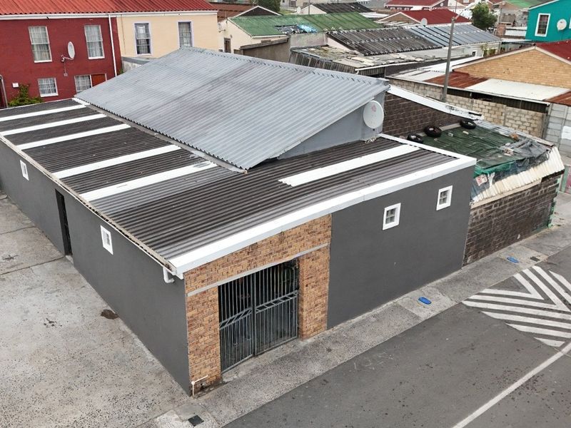 Aerial view of a property featuring a corrugated metal roof, brick facade detailing, and a secure metal gate entrance.