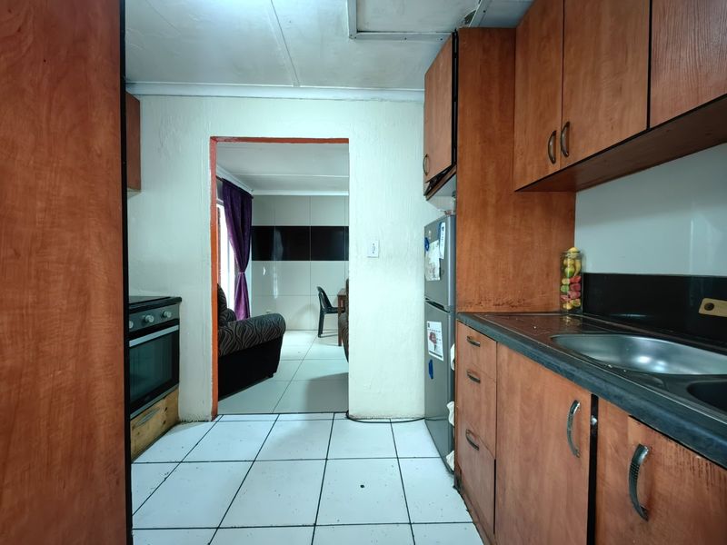 A functional kitchen featuring wooden cabinetry, a built-in oven, and tiled flooring, offering potential for modernization and aesthetic updates.