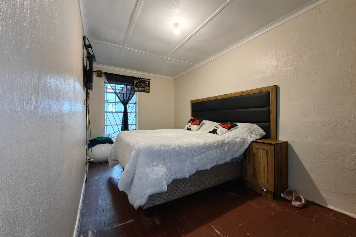 A bedroom featuring a window with security bars and a ceiling with visible cornice detailing.