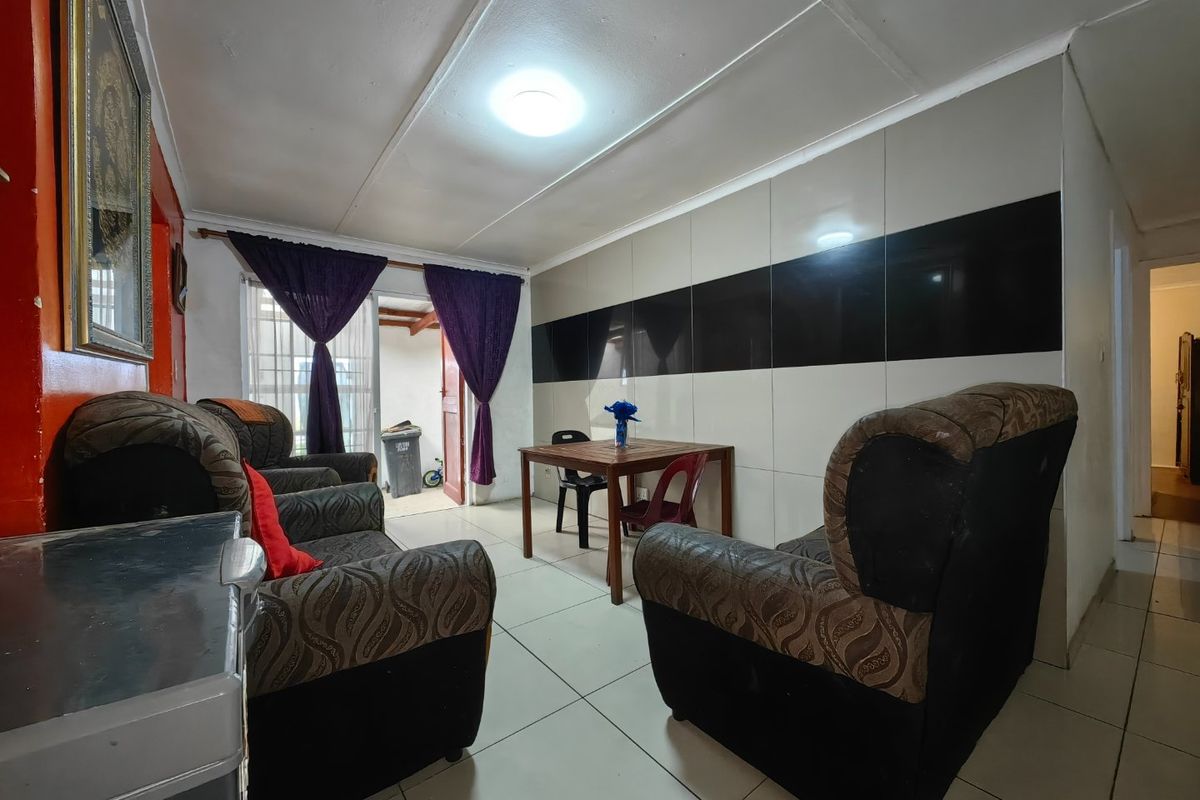 Living room featuring tiled flooring and a decorative glossy tiled feature wall, with direct access to an outdoor area through a sliding glass door.