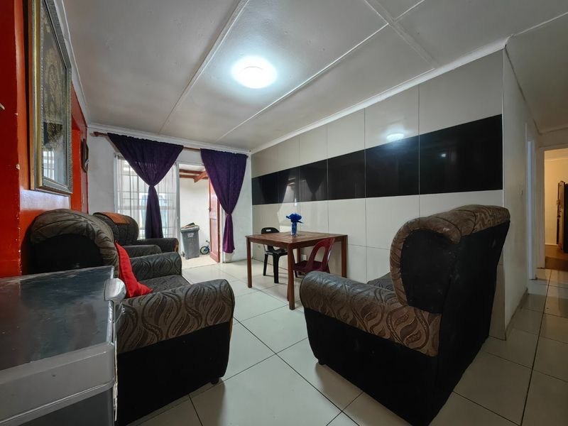 Living room featuring tiled flooring and a decorative glossy tiled feature wall, with direct access to an outdoor area through a sliding glass door.