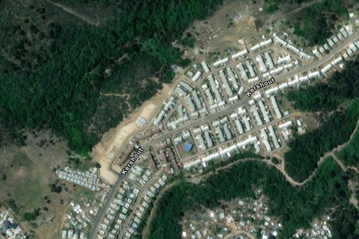 An aerial satellite view showing the layout of a residential housing development and surrounding natural landscape.