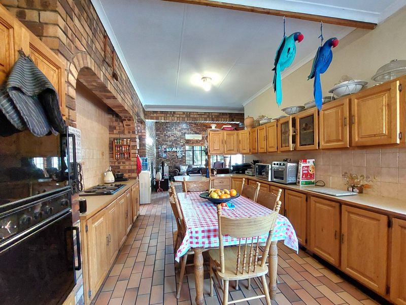 Spacious open-plan kitchen and dining area featuring rustic brick walls, extensive wooden cabinetry, and durable tiled flooring throughout.