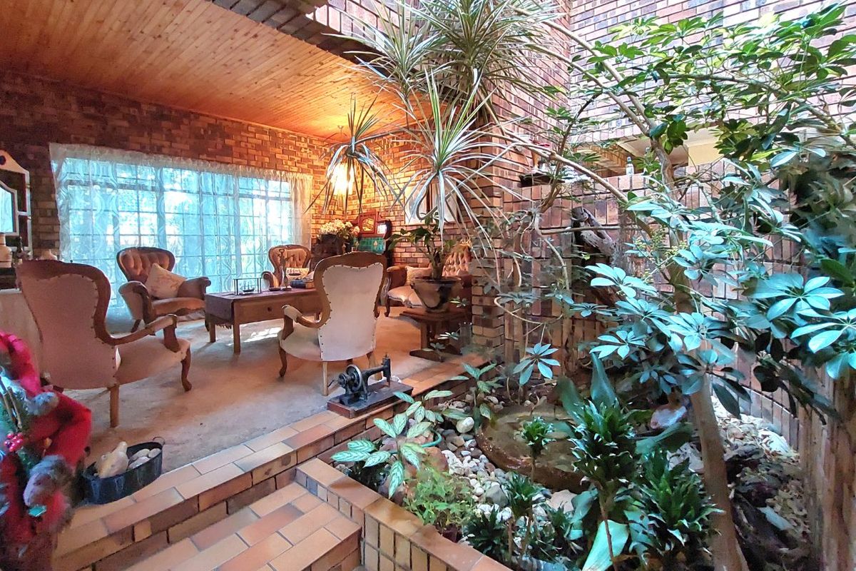 A unique living area featuring exposed brick walls, a timber ceiling, and an integrated indoor garden bed with tiled steps.
