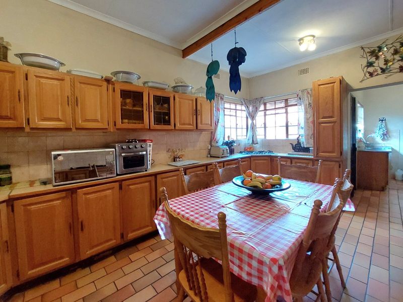 A traditional kitchen featuring wooden cabinetry, tiled flooring, and a tiled backsplash, offering a functional layout with integrated cooking appliances.