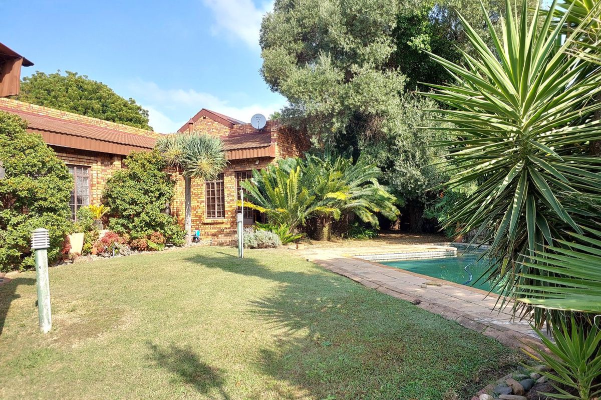 Rear garden view featuring a swimming pool, paved surround, and established landscaping against a face-brick house exterior.