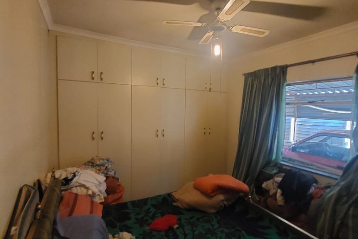 A bedroom featuring built-in cupboards and a ceiling fan, offering functional storage space and basic overhead lighting.