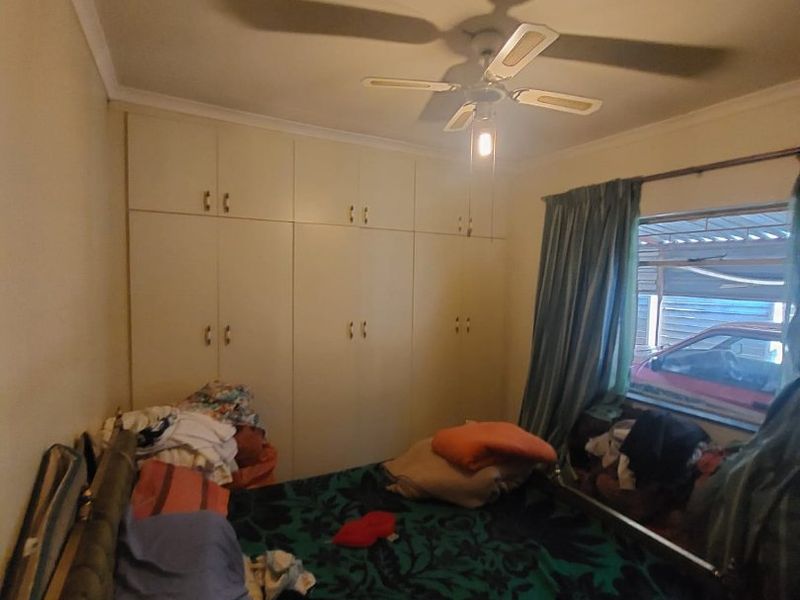 A bedroom featuring built-in cupboards and a ceiling fan, offering functional storage space and basic overhead lighting.