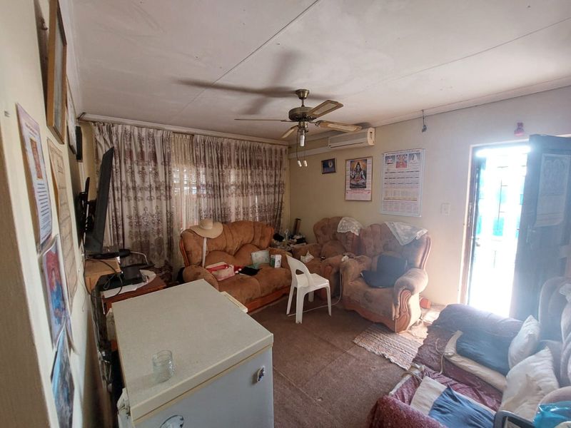 A living room featuring a ceiling fan, split-system air conditioning, and direct access to an exterior security gate.