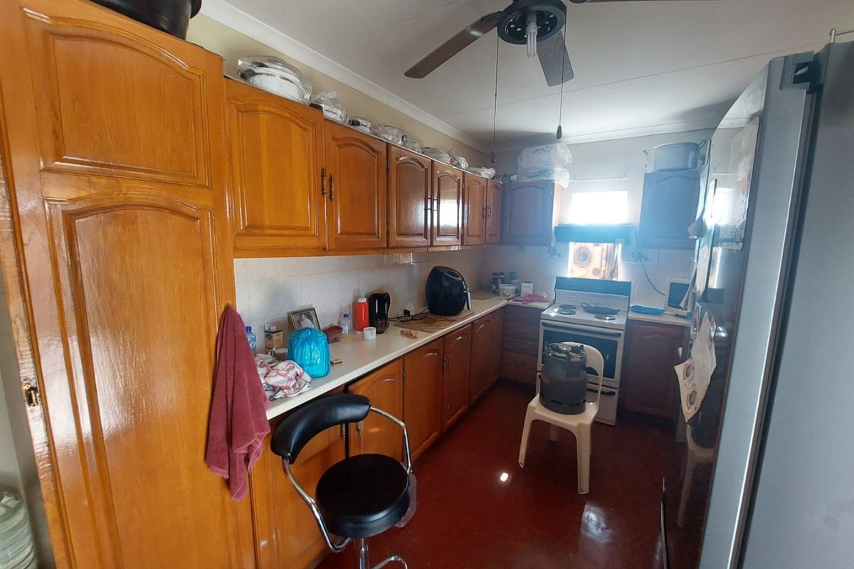 A functional kitchen featuring traditional wooden cabinetry, laminate countertops, and a freestanding stove, offering potential for modernization and aesthetic updates.