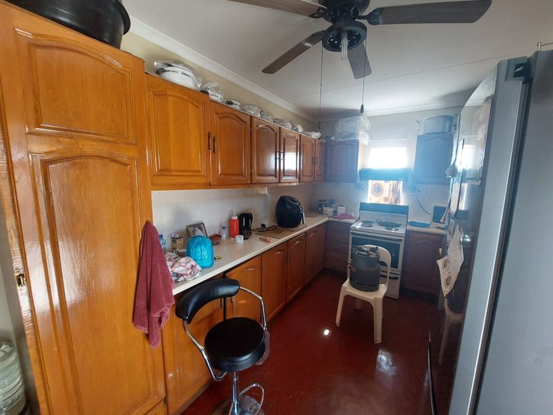 A functional kitchen featuring traditional wooden cabinetry, laminate countertops, and a freestanding stove, offering potential for modernization and aesthetic updates.
